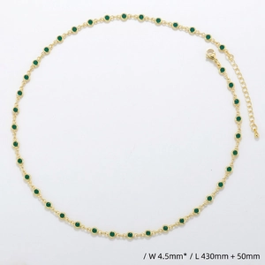 Detailed macro view of a gold chain necklace featuring green round stones with lobster clasp