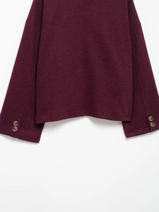 Detailed macro view of burgundy wool coat showing sleeve cuffs and tortoiseshell buttons