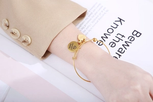 Detail of adjustable gold wire bracelet with Love You Grandma and Hope heart charms