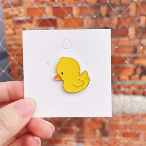 Cute yellow enamel duck brooch pin on handmade jewelry card displayed by hand