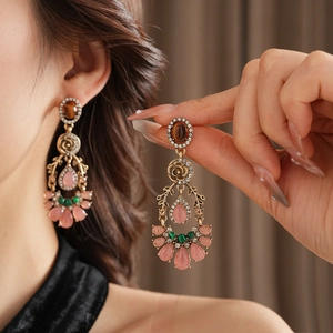 Dettaglio di orecchini vintage stile palazzo con fiori rosa e gocce di strass lucidi