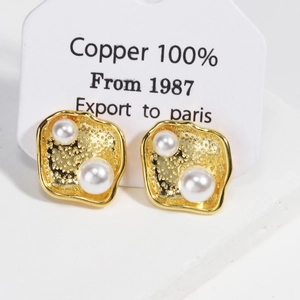 Detailed macro of 18k gold plated hammered texture earrings with dual white pearls