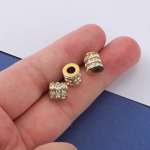 Detailed macro view of three gold cylinder spacer beads with triple-row rhinestones
