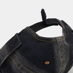 Detail of adjustable Velcro strap on washed blue denim docker cap with contrast stitching