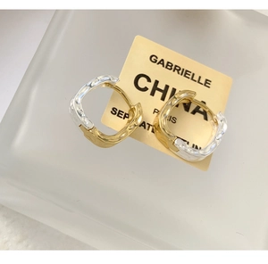 Macro shot of two-tone silver and gold earrings with irregular lava texture detail