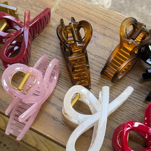 Detail of assorted large resin shark hair claws in multiple colors on a wooden surface
