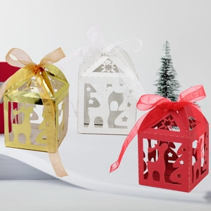 Macro detail of laser-cut reindeer and star patterns on house-shaped Christmas gift boxes
