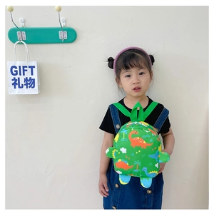 Detail of green cartoon dinosaur backpack with orange spikes on a child model