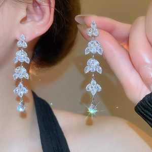 Detailed view of silver leaf tassel earrings with sparkling rhinestones on model
