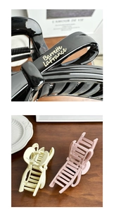 Detail of elegant hair claw clips in black, beige, and pink with gold lettering