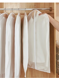 Detail view of white translucent PEVA garment bags with smooth zipper inside a closet