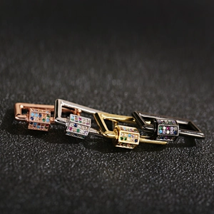 Macro detail of four-color zircon-inlaid 18K gold-plated clasps on black texture