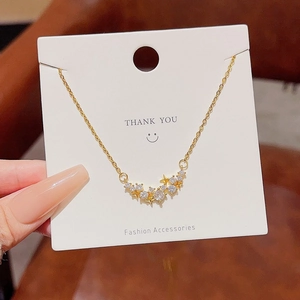 Macro shot of gold star necklace with zircon stones on a white branded display card