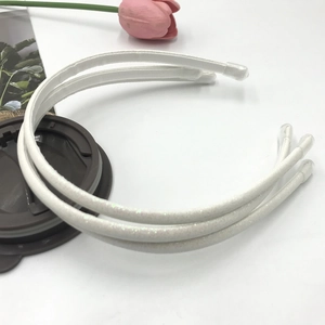 Close-up of three white glitter headbands with protective caps on a white surface