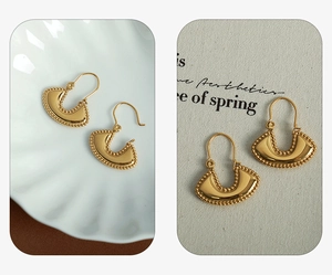 Close-up of vintage gold fan-shaped hoop earrings with intricate beaded edge texture