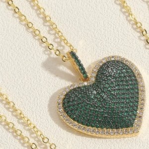 Macro view of heart pendant with emerald green zircon pavé and gold plating details