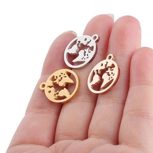Detailed view of silver, gold, and rose gold world map pendants on a hand for scale