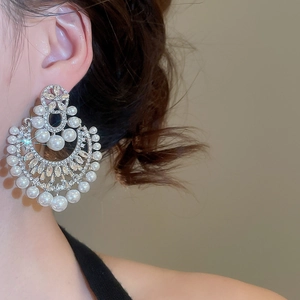 Primo piano di orecchini di lusso a fiore con perle e cristalli indossati da una modella