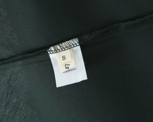 Detail shot of the size S and origin label on a dark green backless maxi dress