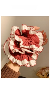 Close-up of oversized red and white pleated hair scrunchie with scalloped edge detail