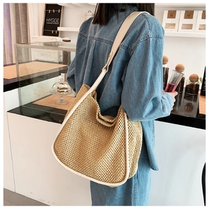 Detail of hand-woven straw tote bag with white faux leather trim and shoulder strap