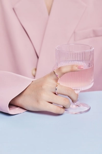 Detailed view of colorful baguette-cut zircon rings worn on hand with a pink blazer