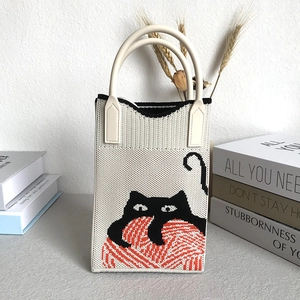 Minimalist knit handbag with black cat and red ball pattern in cream white fabric