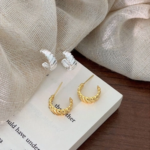 Close-up of twisted 925 silver C-shape stud earrings in gold and silver finish