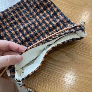 Detail view of houndstooth crossbody bag featuring magnetic snap and canvas lining