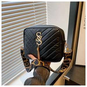 Detail of black quilted leather crossbody bag with gold SS logo and tassel charm
