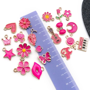 Pink enamel charms set with heart, butterfly and crown shapes on white background