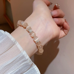 Détail du bracelet en perles d'œil de chat champagne avec des breloques étoiles en argent