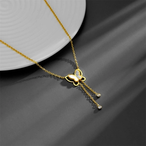 Collier papillon doré avec incrustation de nacre et glands sur fond gris foncé
