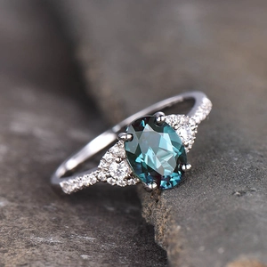Macro-opname van ovale groenblauwe edelsteen ring met diamanten op grijze rots