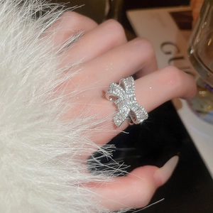 Close-up of sparkling zircon bow ring on finger with detailed hollow-out craftsmanship