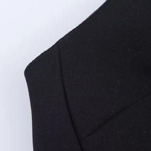 Close-up detail showing black woven fabric texture and stitching on halter neck dress