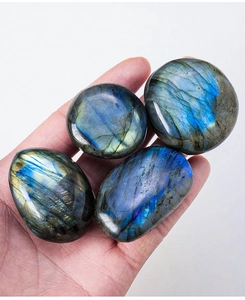 Detail of four natural labradorite stones showing blue and gold flashes on a hand