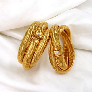 Macro detail of golden Tubogas spiral bracelet featuring a clear zircon inlay connector