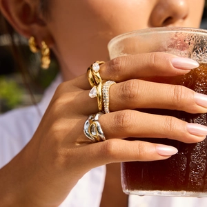 Close-up of stacked gold rings with crystals and pear-shaped stone on a hand
