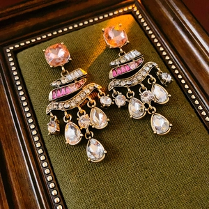 Detail of vintage gold earrings with pink gemstones and waterdrop tassels in a velvet frame