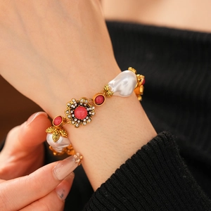 Detail of a vintage gold flower bracelet with pearls and red crystals on a model wrist
