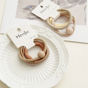 Detailed close-up of earth-toned hair bands with beads on a decorative ceramic tray
