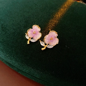 Macro shot of purple crystal flower earrings with marquise zircon leaves on green velvet