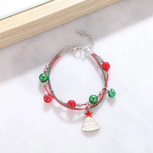 Close-up of woven Christmas bracelet with bells and a green Christmas tree charm
