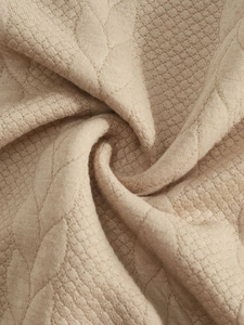 Macro detail of beige jacquard knit fabric showing premium texture and waffle weave pattern