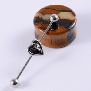 Macro shot of stainless steel industrial barbell with a sliding heart cross pendant