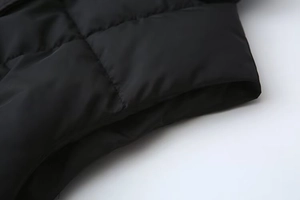 Dettaglio del gilet trapuntato nero con cuciture orizzontali e trama imbottita