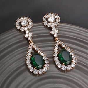 Detailed macro view of teardrop emerald earrings with white zircon accents in gold plating
