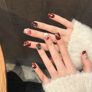 Berry red French press-on nails with bow rhinestones and black gem accents