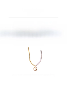 Détail du collier de perles et chaîne dorée avec un pendentif lettre G serti de zircons